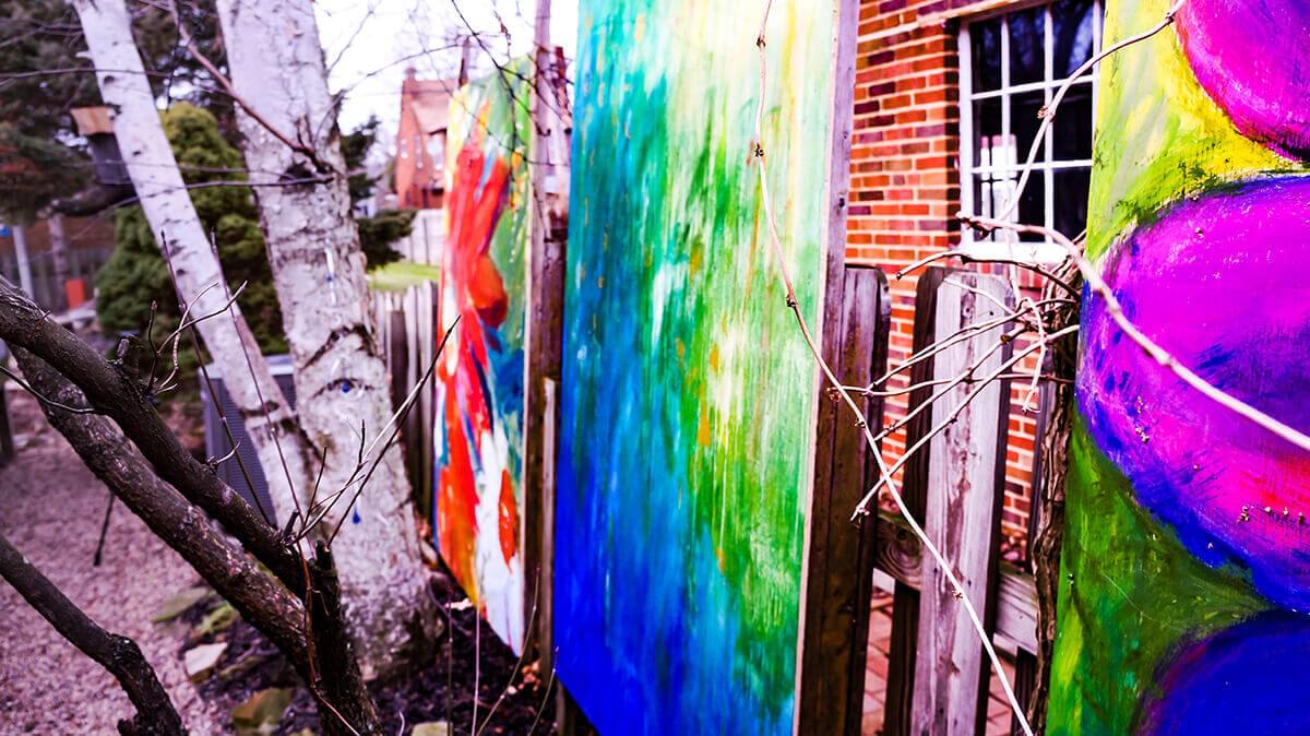 Outdoor colorful abstract paintings along wood fence